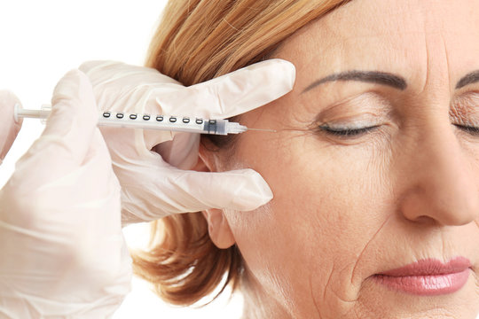 Older woman getting crows feet filler injections