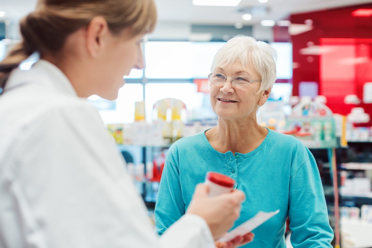 Pharmacist providing medication to elderly customer