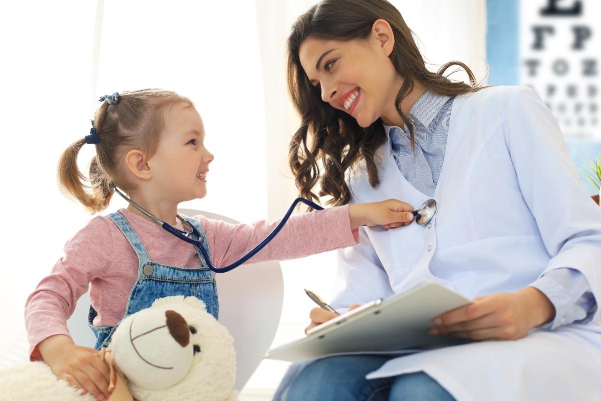 Young happy child using stethoscope on woman 